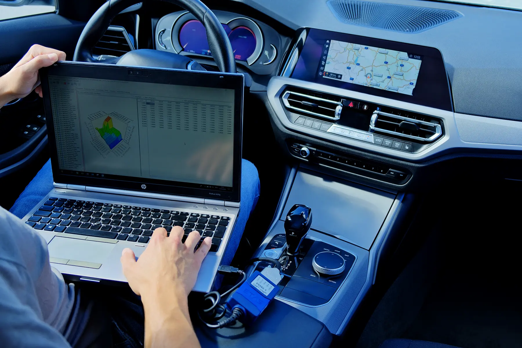 Ingenieur mit Laptop im Innenraum eines Pkw bei der Motorapplikation